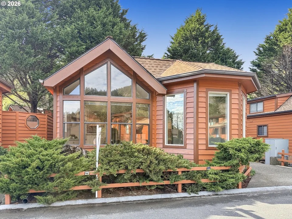 Great room of a new cedar home with a wall of windows facing the trees